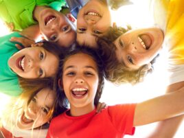 Group of happy little children playing together, having fun, huddling, looking down and smiling